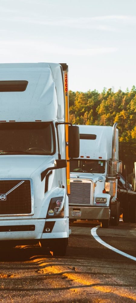 Three semi trucks driving on a highway through a forested landscape in Arizona.